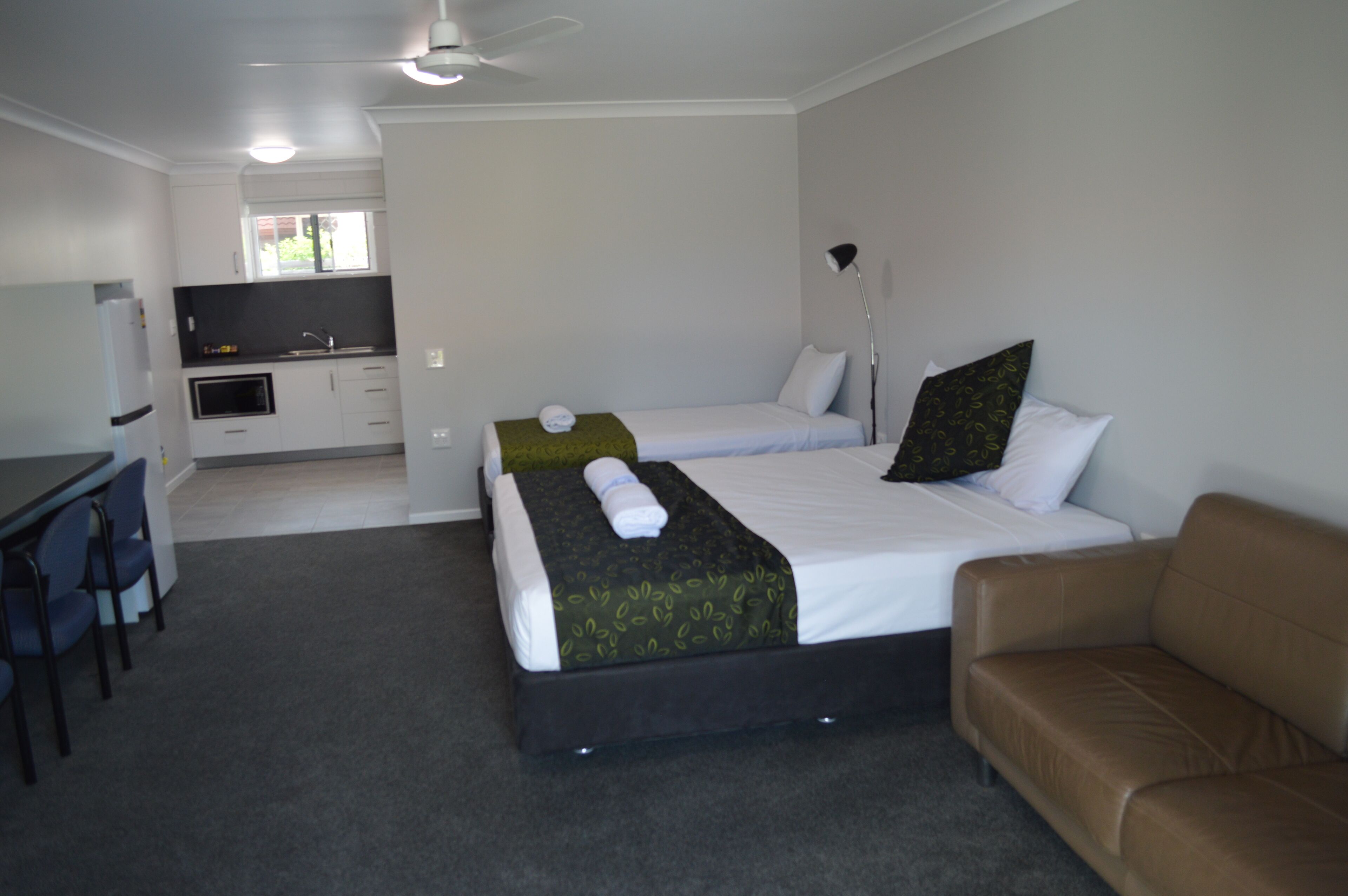 A hotel room with a bed, a sofa, a desk, and a kitchenette.