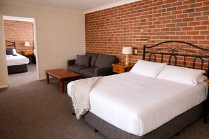 A bedroom with a bed, a sofa, a nightstand, and a lamp. - Poachers Paradise Motel (Rutherglen)