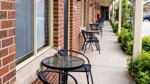 A covered outdoor seating area with brick walls, black metal chairs, and tables. - Poachers Paradise Motel (Rutherglen)