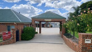 A brick building with a reception area, a sign for 'POACHERS PARADISE MOTEL,' and a number '97' on a wall. - Poachers Paradise Motel (Rutherglen)