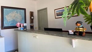 A reception desk with a welcome sign, a framed map, and a framed photograph on the wall. - Poachers Paradise Motel (Rutherglen)