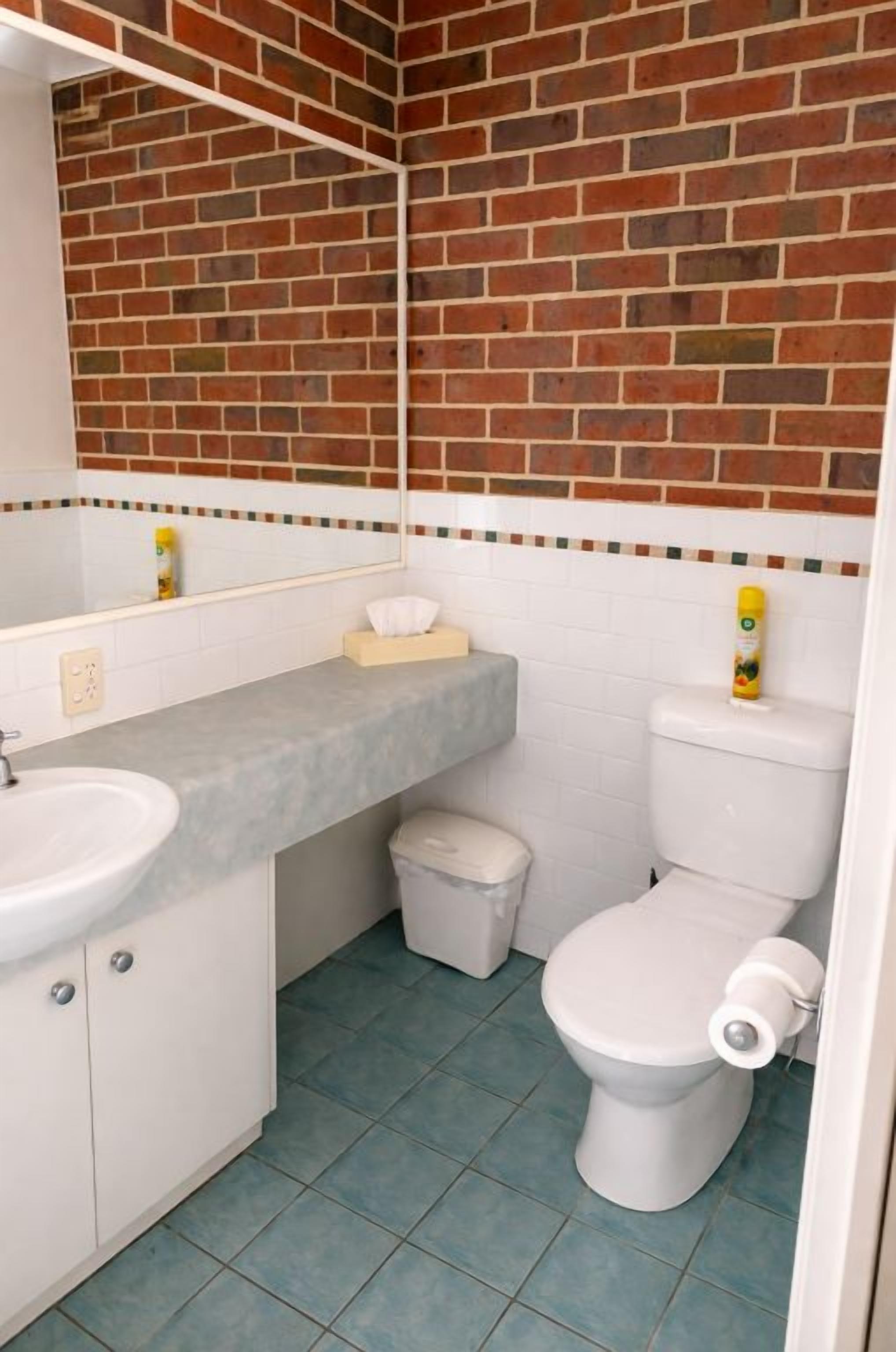 Un baño pequeño con un lavamanos blanco, un inodoro y un cubo de basura.