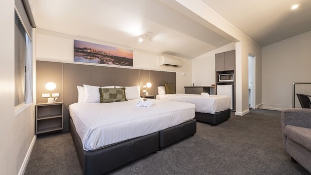 A hotel room with two beds, a desk, a chair, a microwave, and a small kitchenette. - Fern Bay Motel  (Fern Bay)