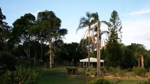 A grassy area with a white gazebo, surrounded by trees and shrubs. - Fern Bay Motel  (Fern Bay)