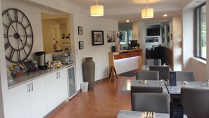 A modern restaurant with a large wall clock, a coffee machine, and a counter with a menu. - Fern Bay Motel  (Fern Bay)