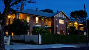 A two-story brick building with multiple windows, a gated entrance, and a well-maintained hedge in front. - The Old Parkes Convent (Parkes)