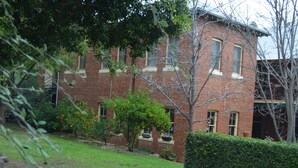 A brick building with multiple windows and a well-maintained garden. - The Old Parkes Convent (Parkes)