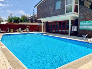 Una piscina al aire libre, sillones reclinables de piscina