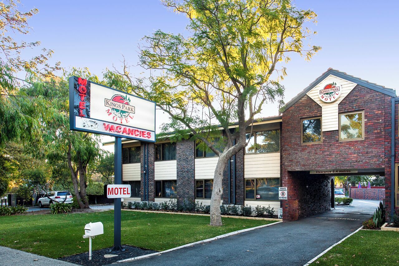 A Kings Park Motel with a clear sign, a brick building, and a parking area.