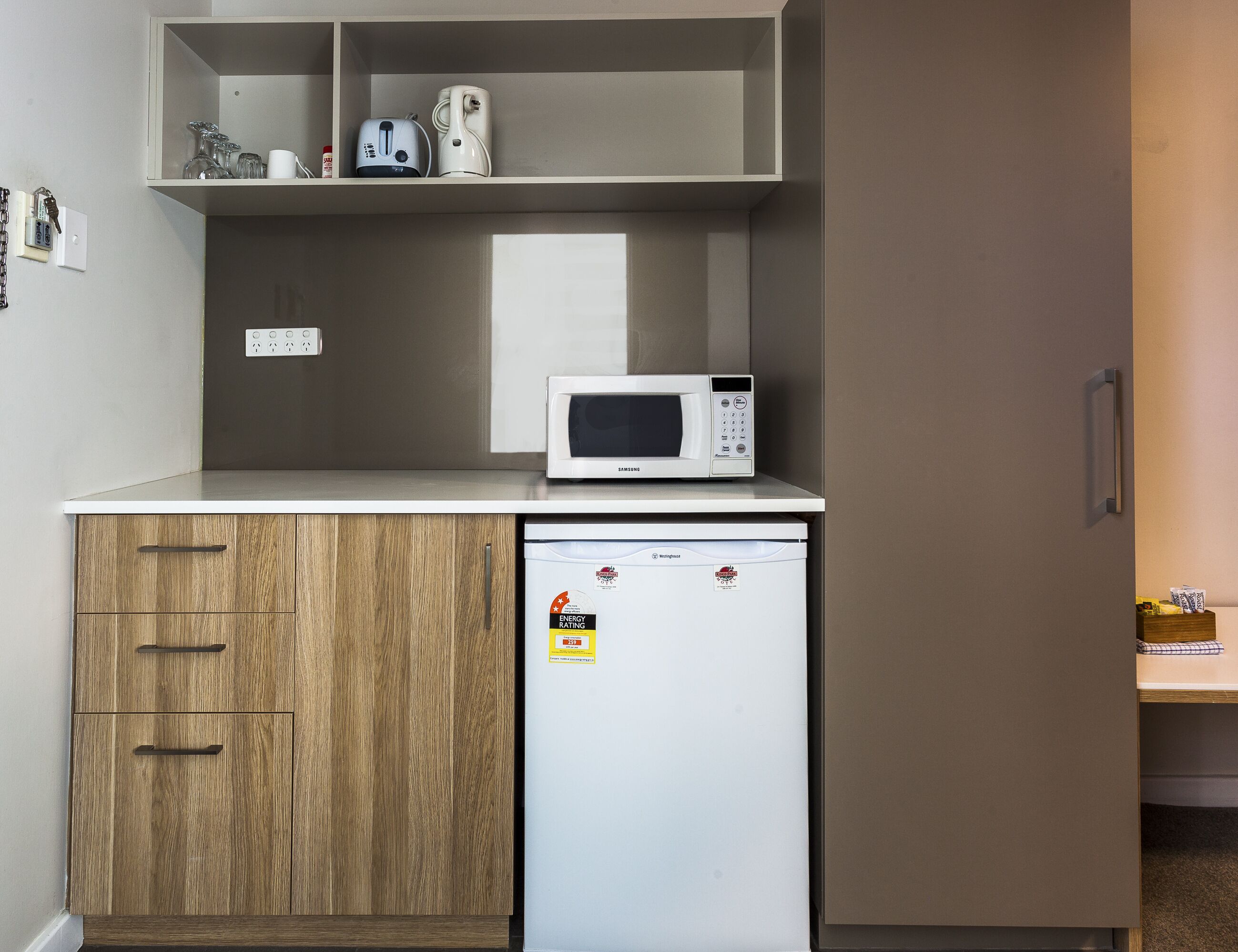 Une petite cuisine équipée d’un four à micro-ondes, d’un petit réfrigérateur et d’un meuble avec des tiroirs.