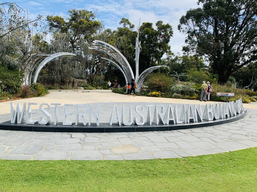A sign with "WESTERN AUSTRALIA BOTANIC GARDEN" written on it, surrounded by greenery and trees.