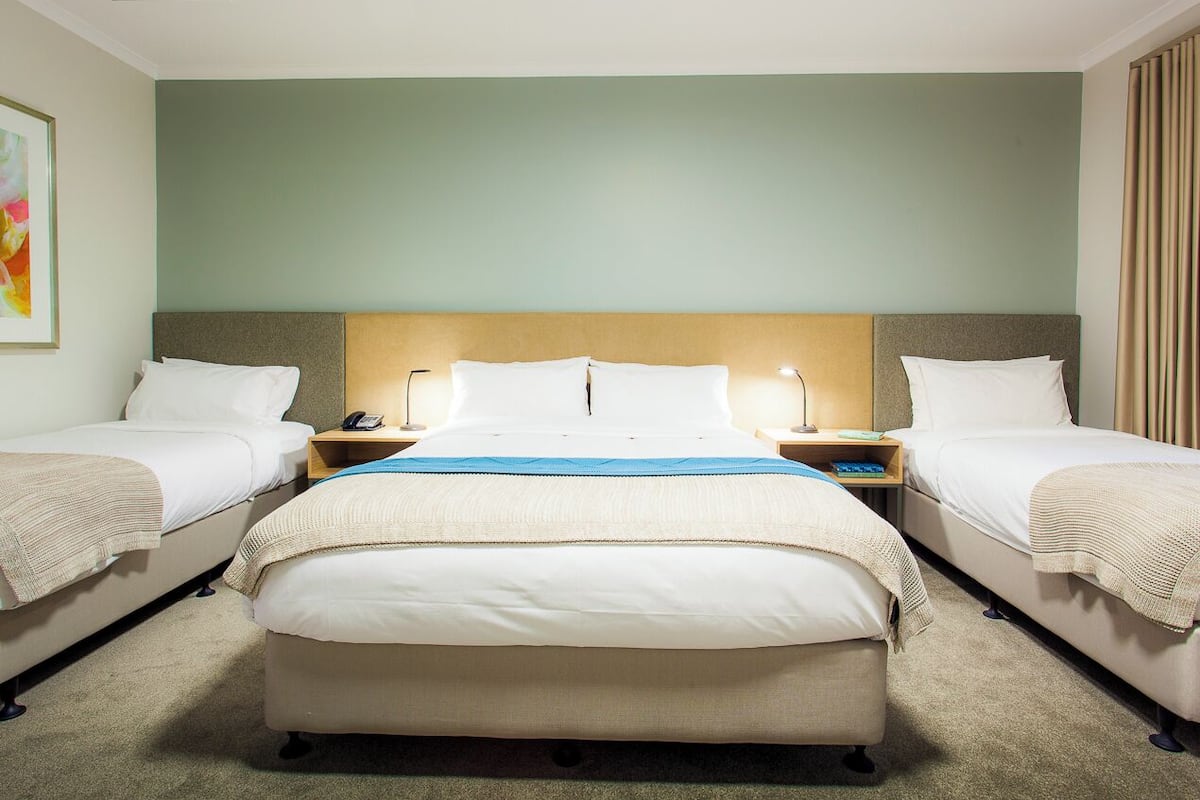 Ein Hotelzimmer mit einem großen Bett, zwei Nachttischen und einem Kopfteil.