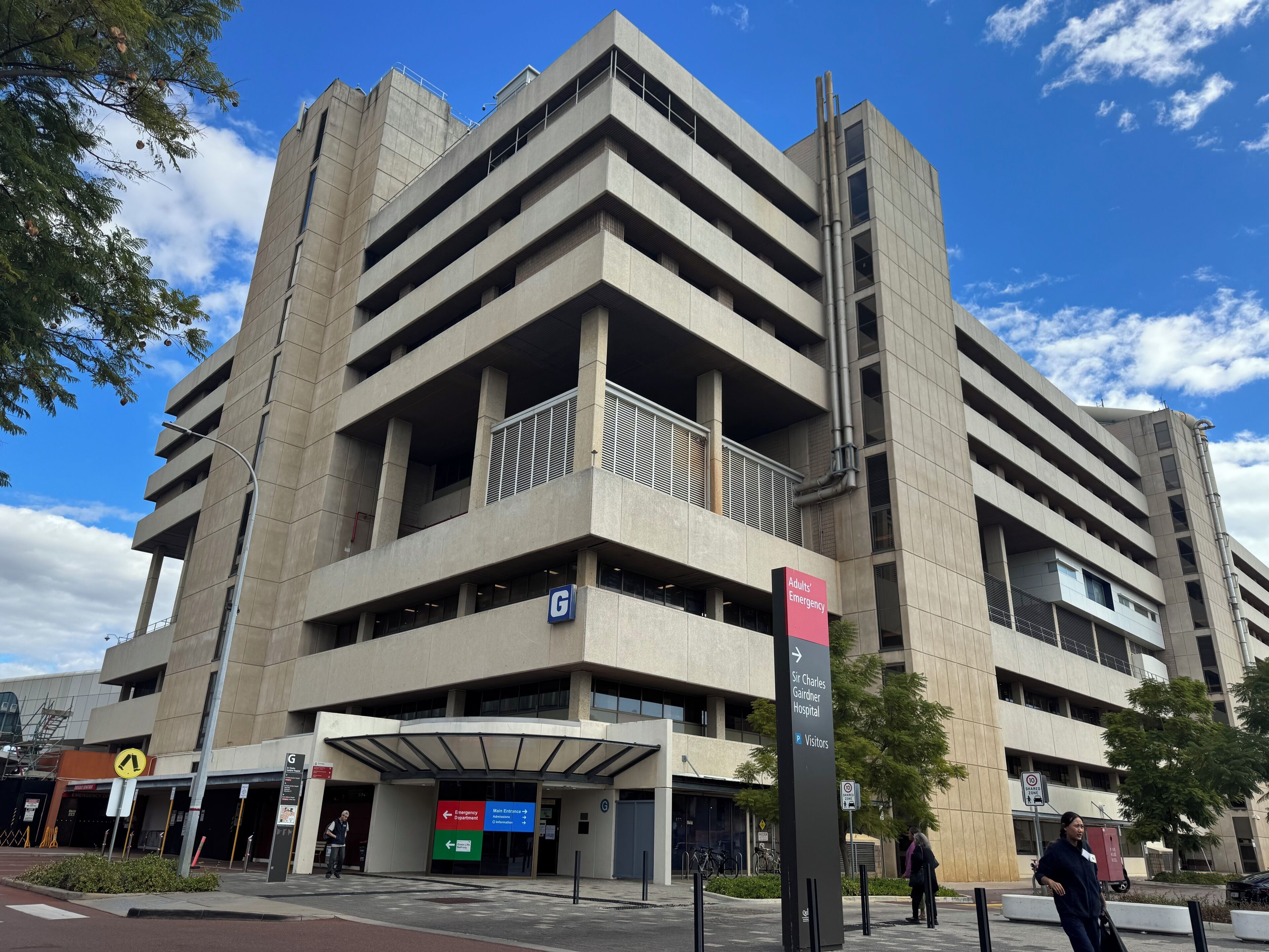 A multi-story parking garage with a sign indicating an emergency exit and a visitor entrance.