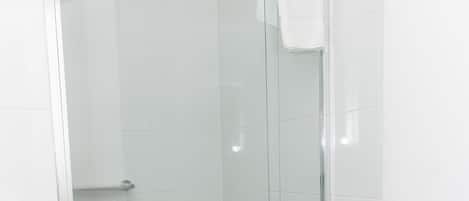 A glass-enclosed shower stall with a white towel hanging on the door handle.
