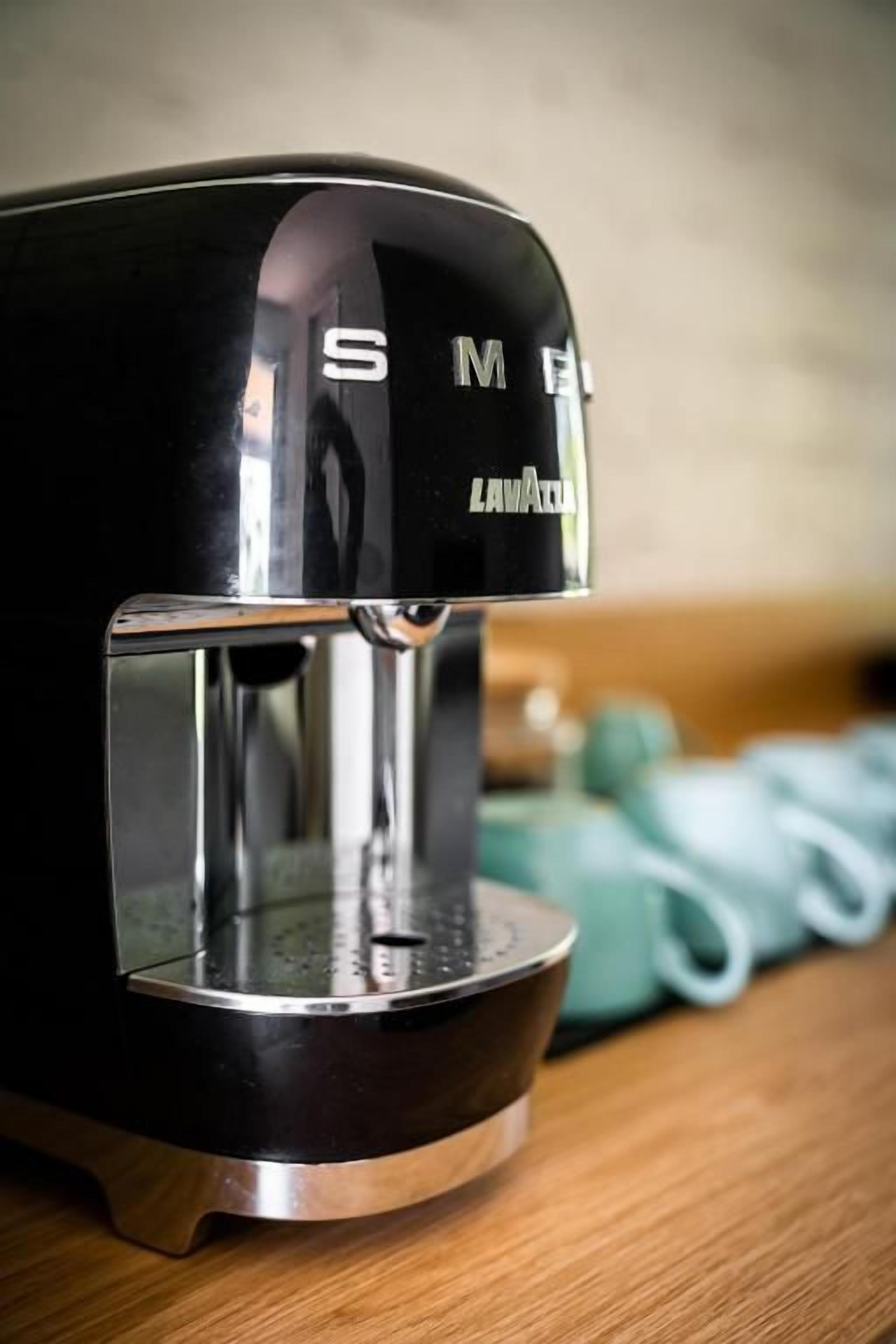 A black coffee maker with a metallic base on a wooden surface.