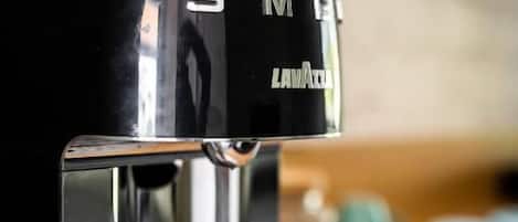 A black coffee maker with a metallic base on a wooden surface.