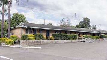 A motel with a brick facade, numbered rooms, and a parking lot.