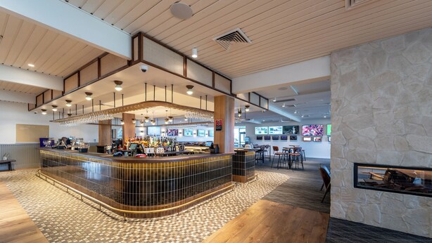 A modern bar area with a curved counter, wooden flooring, and a stone accent wall.