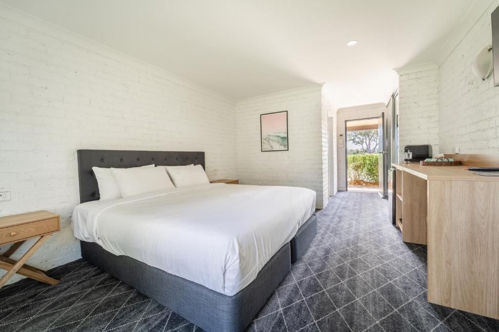 A bedroom with a bed, bedside table, and a desk with a chair.