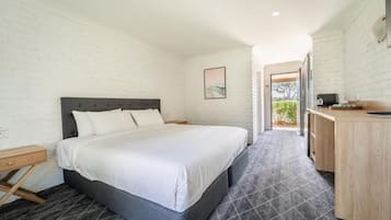 A bedroom with a bed, bedside table, and a desk with a chair.