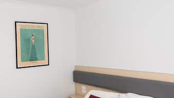 A bedroom with a bed, a nightstand, a red pillow, and a framed poster on the wall.