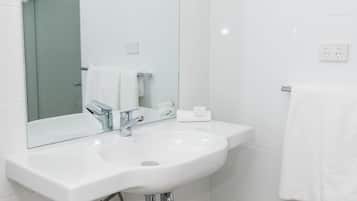 Uma casa de banho moderna com uma pia branca, torneira cromada e um espelho em cima.