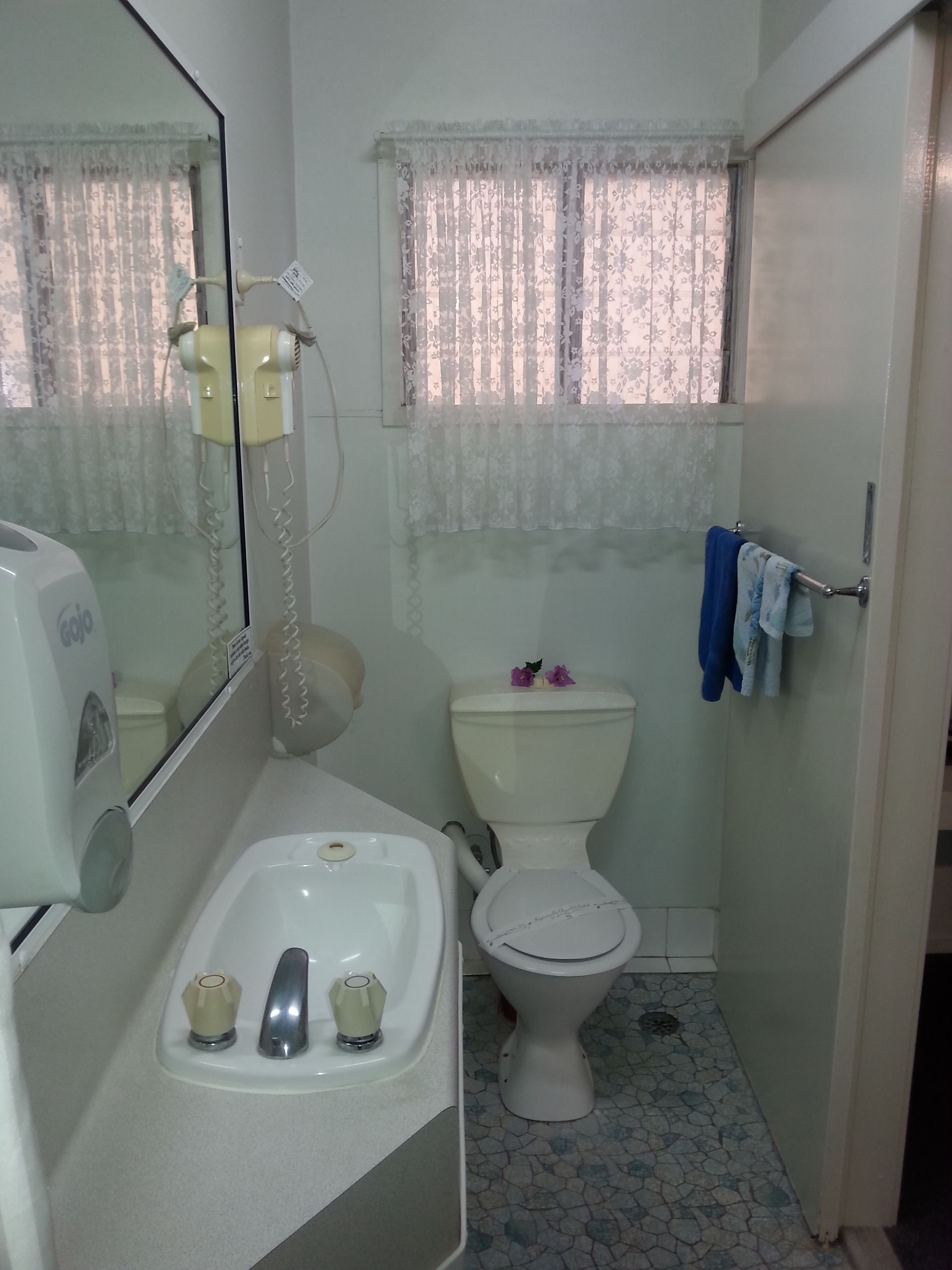 Un baño pequeño con inodoro, lavamanos y espejo.
