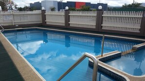 A swimming pool with a white picket fence and a tiled edge. - Golden Fountain Motel (Allenstown)