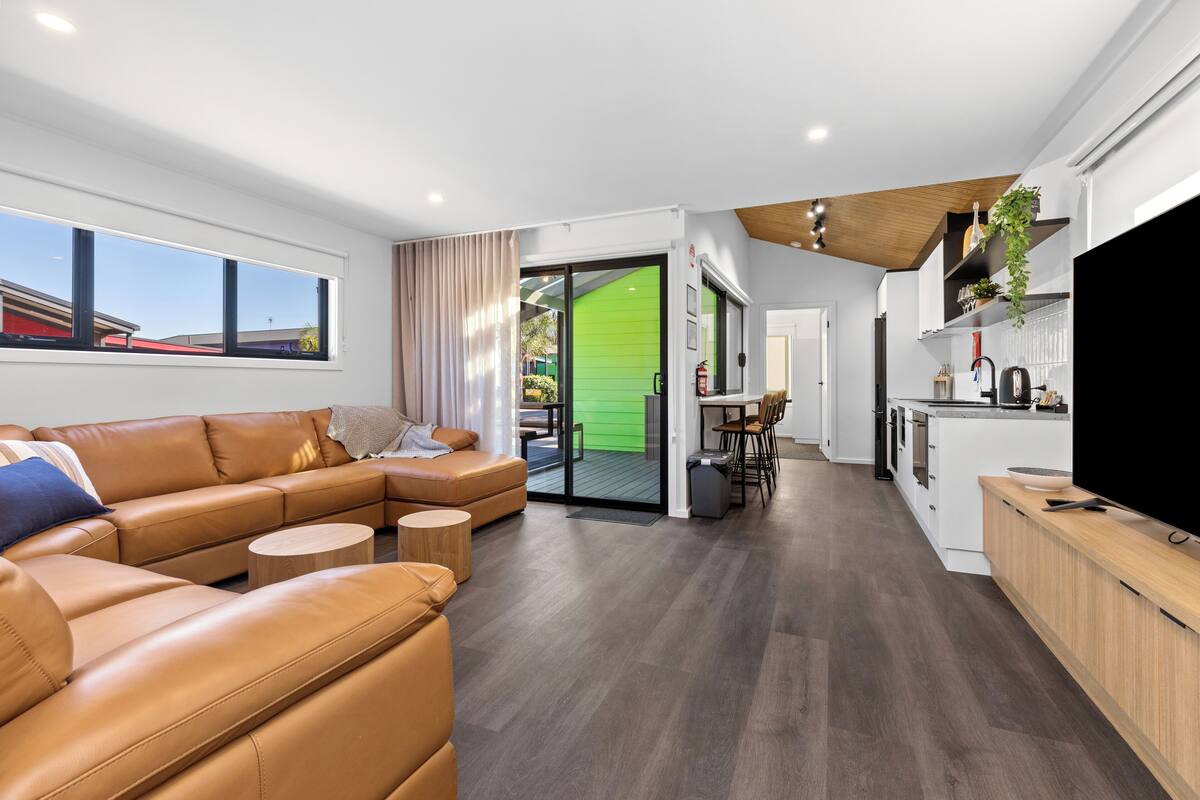 Una sala moderna con un sofá de cuero, un comedor y una cocina.