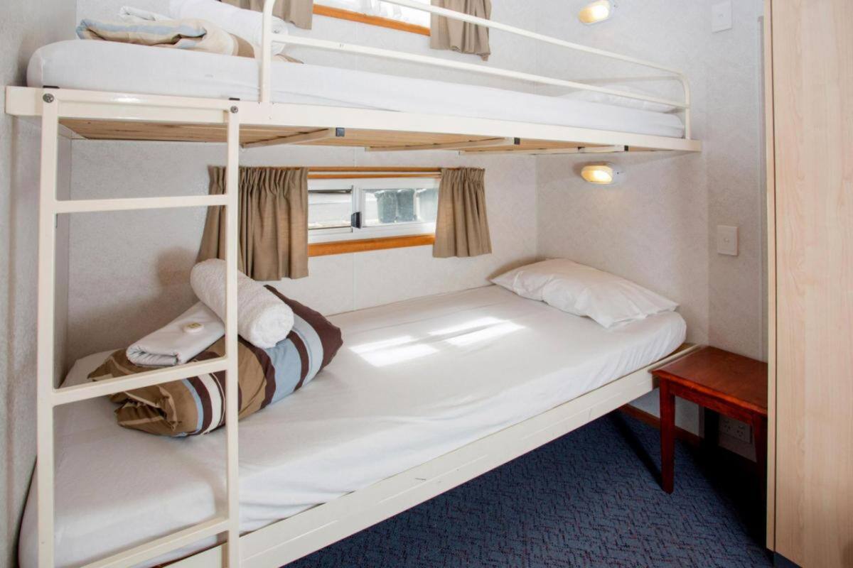 Dormitorio con literas, ventana, cortinas y una pequeña mesa de madera.