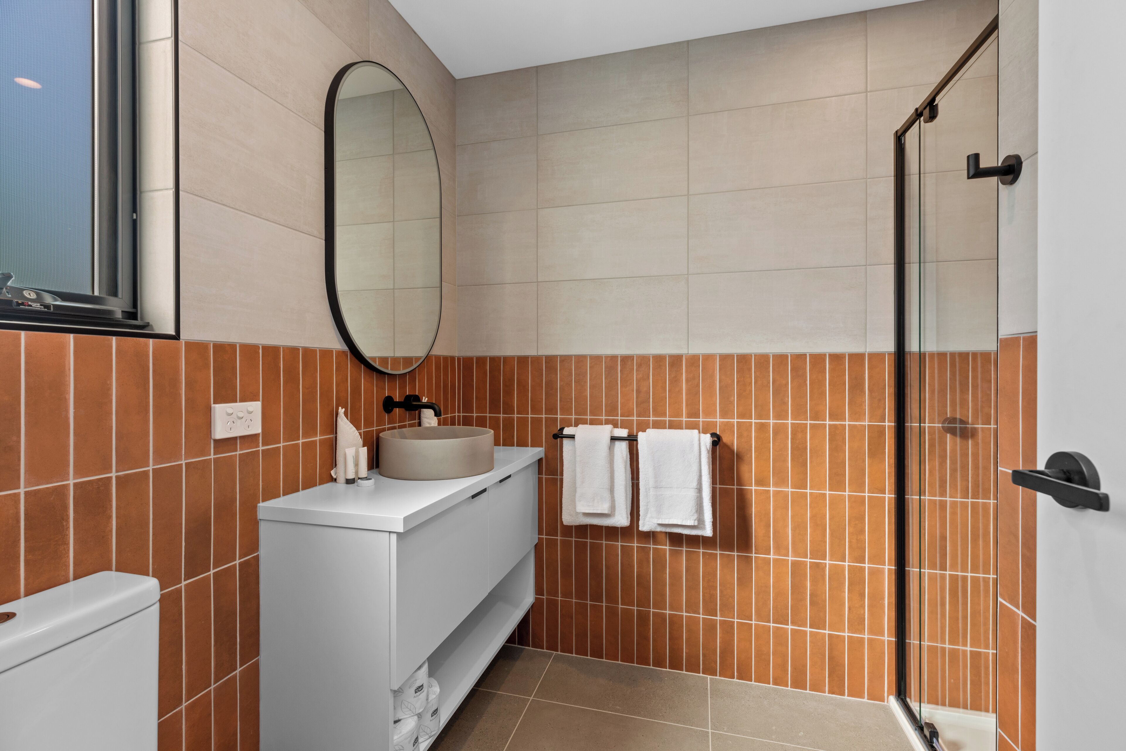 A modern bathroom with a large mirror, a sink, and a shower area.