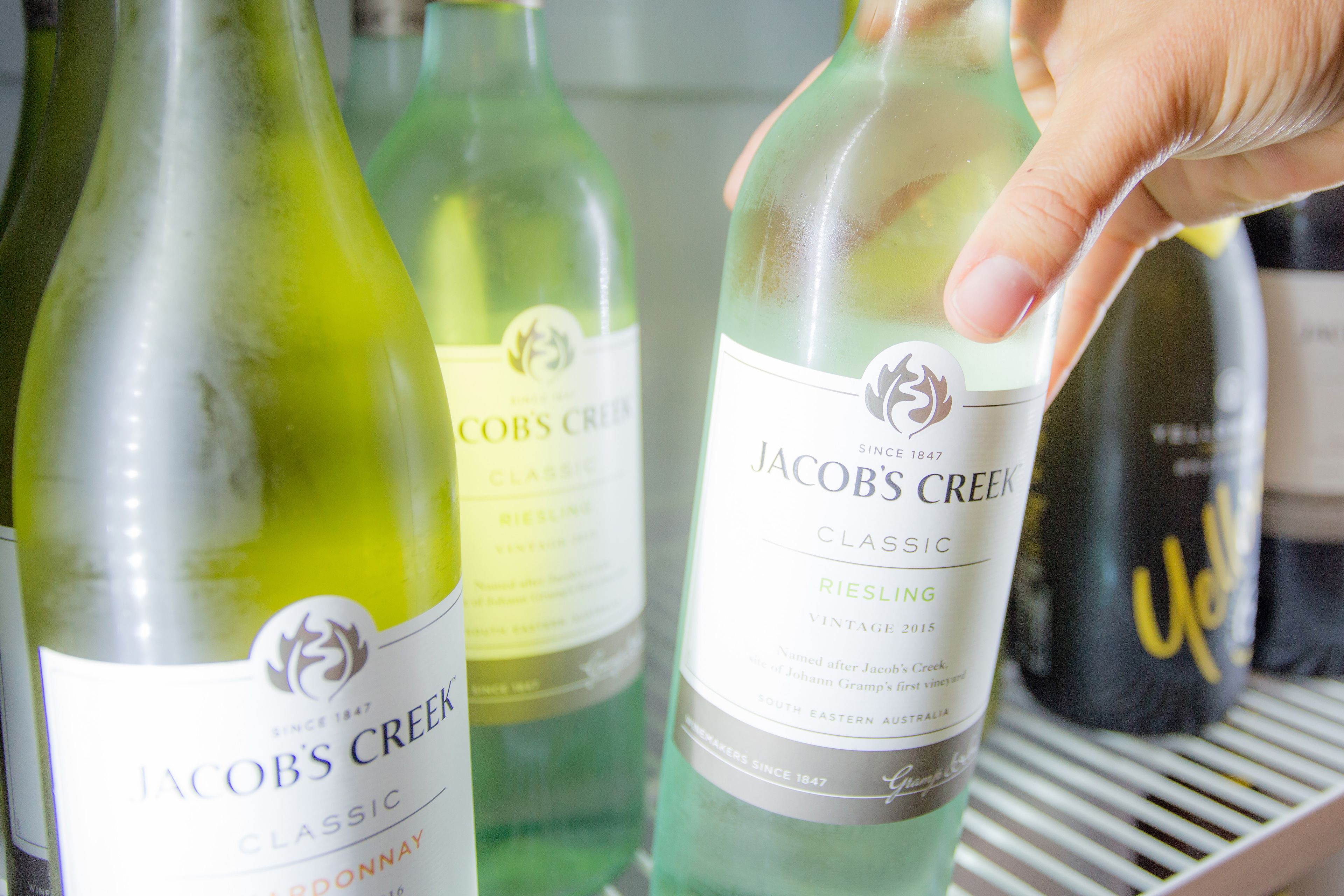 Eine Hand, die eine Flasche Jacob's Creek Wein hält.