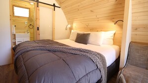 Une chambre à coucher avec un lit, une table de chevet, un plafond en bois et une fenêtre.