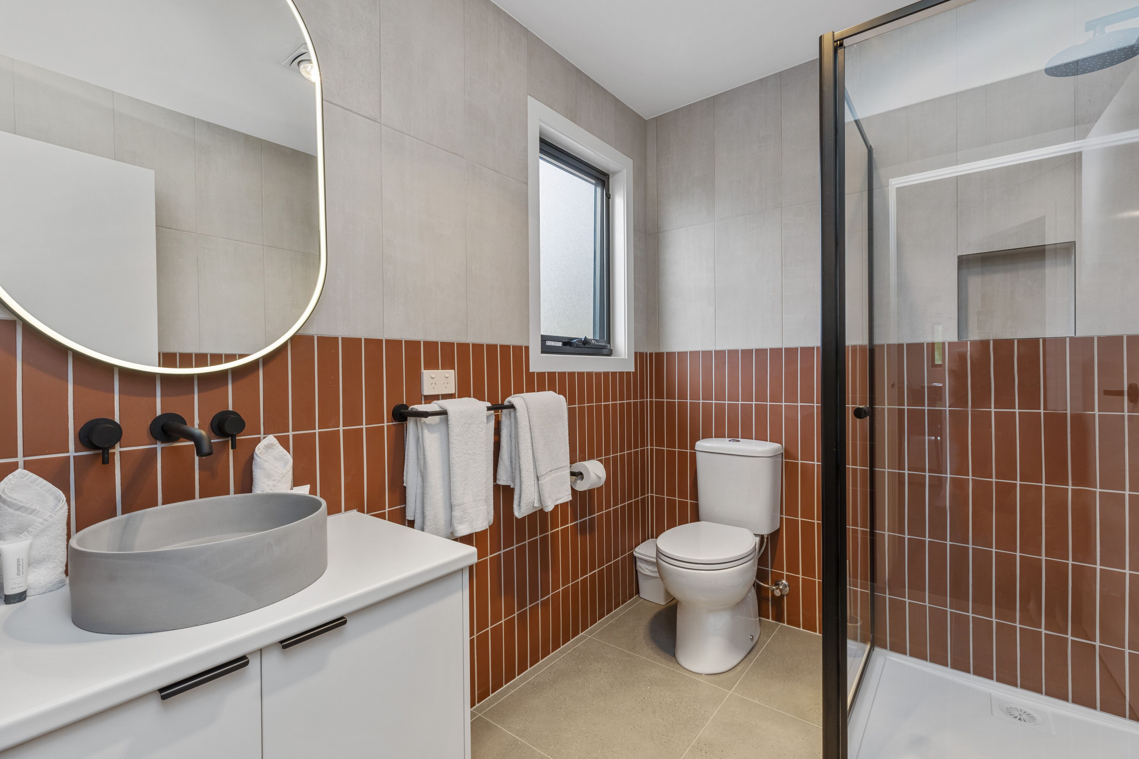 A modern bathroom with a large sink, toilet, and shower.