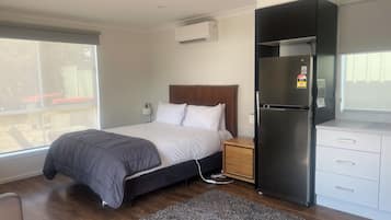Quarto de hotel moderno com cama, mesa de cabeceira, frigorífico e janela com vista para o exterior.