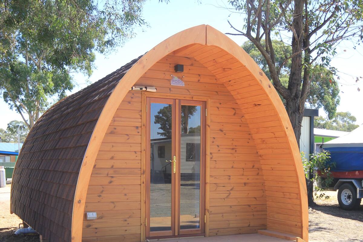 Una pequeña estructura de madera con arco, puerta de vidrio y un letrero encima.