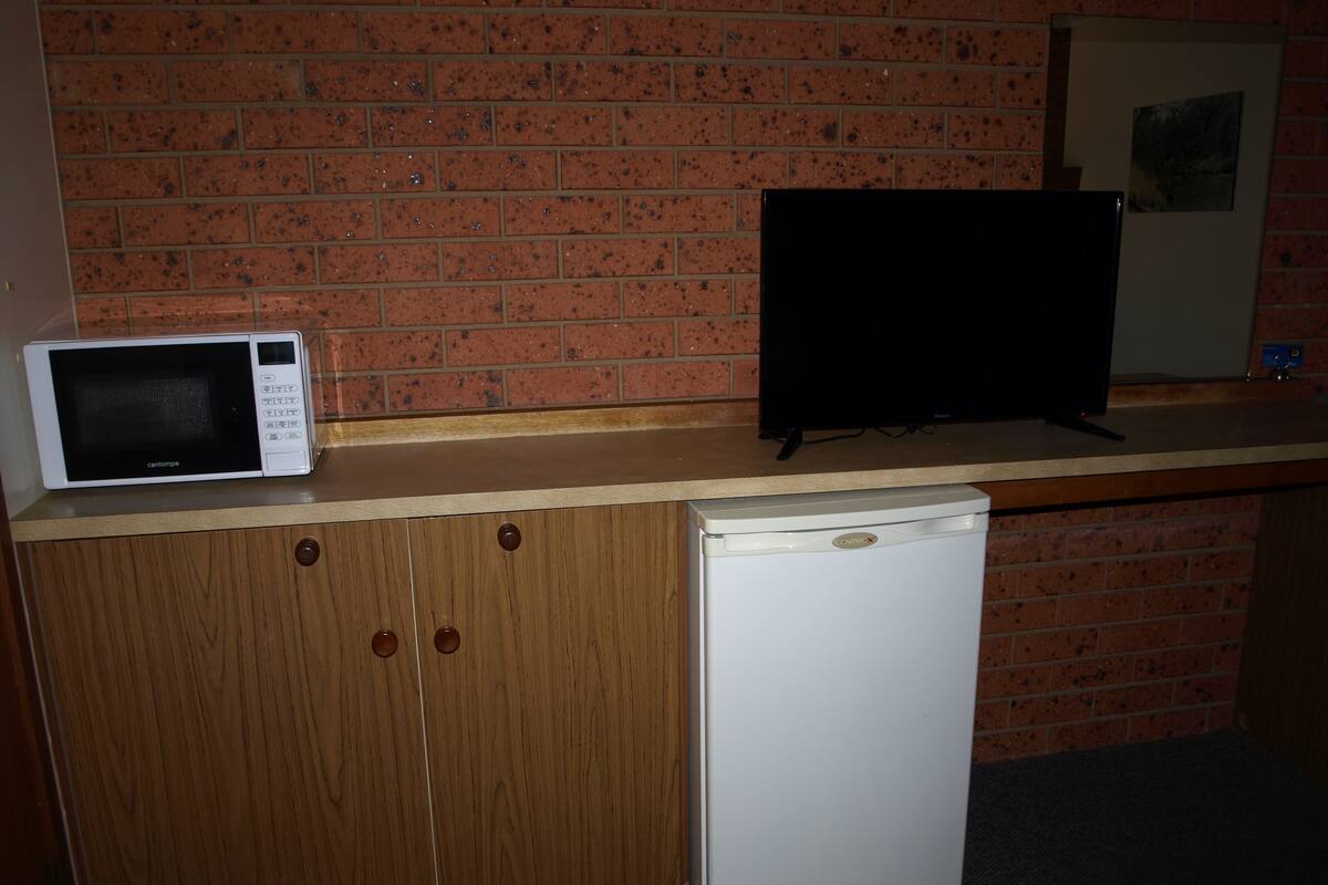 A kitchenette with a microwave, a television, and a refrigerator.