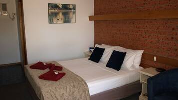 Ein Hotelzimmer mit einem Bett, einem Nachttisch, einer Ziegelwand, einem Gemälde und einem blauen Stuhl.
