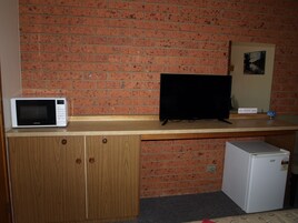 Una kitchenette con microondas, un televisor de pantalla plana negro y un refrigerador.