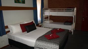 A hotel room with a single bed, a bunk bed, a painting on the wall, and a red door.