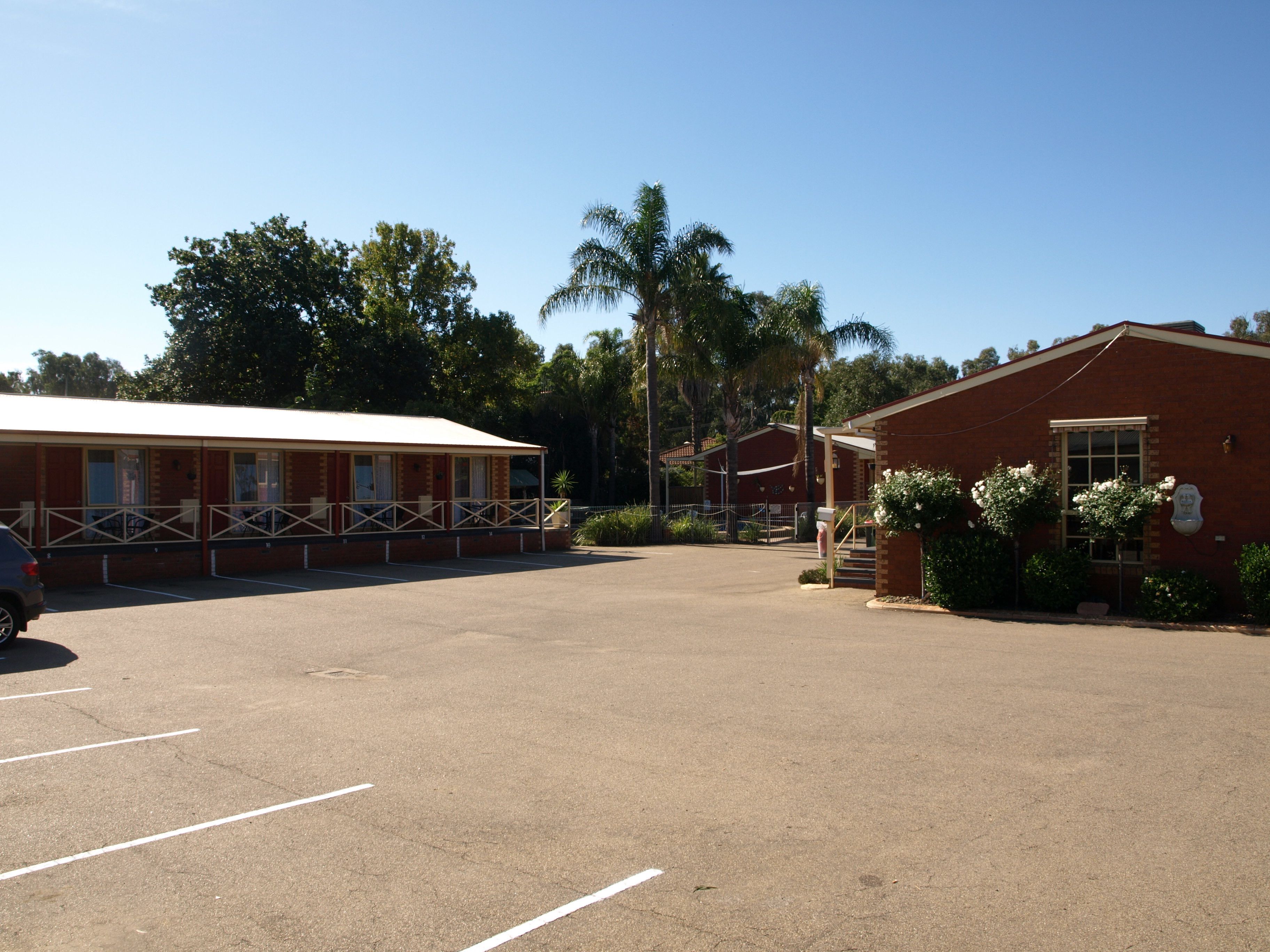 A parking lot with a building that has a covered area with windows and a balcony.