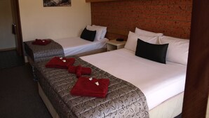 Habitación de hotel con dos camas, una pared de ladrillo y un cuadro en la pared.