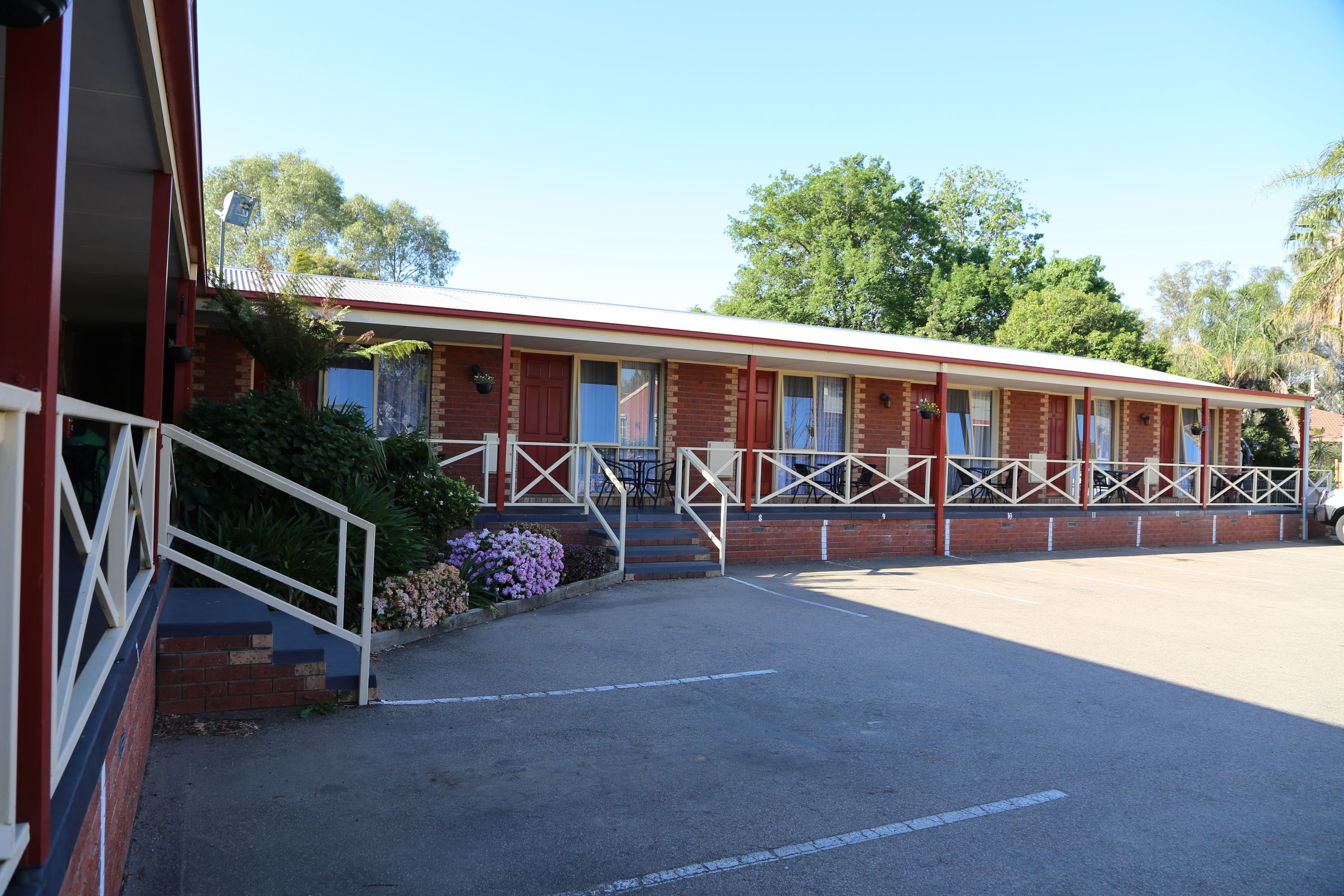 Ein Motel mit roter Fassade, Ziegelwänden und einem überdachten Parkbereich.