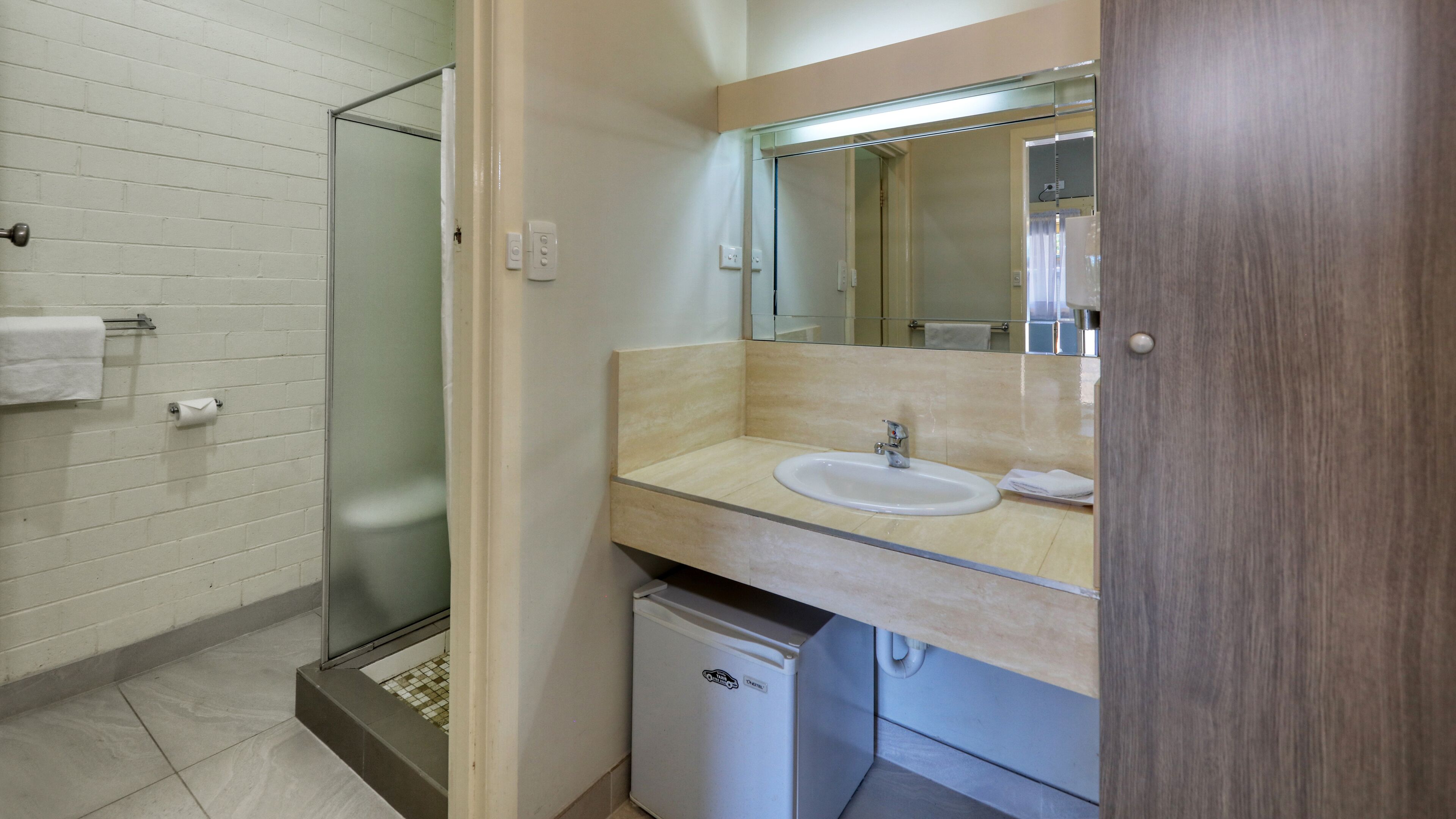 Un baño con cabina de ducha de vidrio, un lavamanos y un espejo sobre el lavamanos.