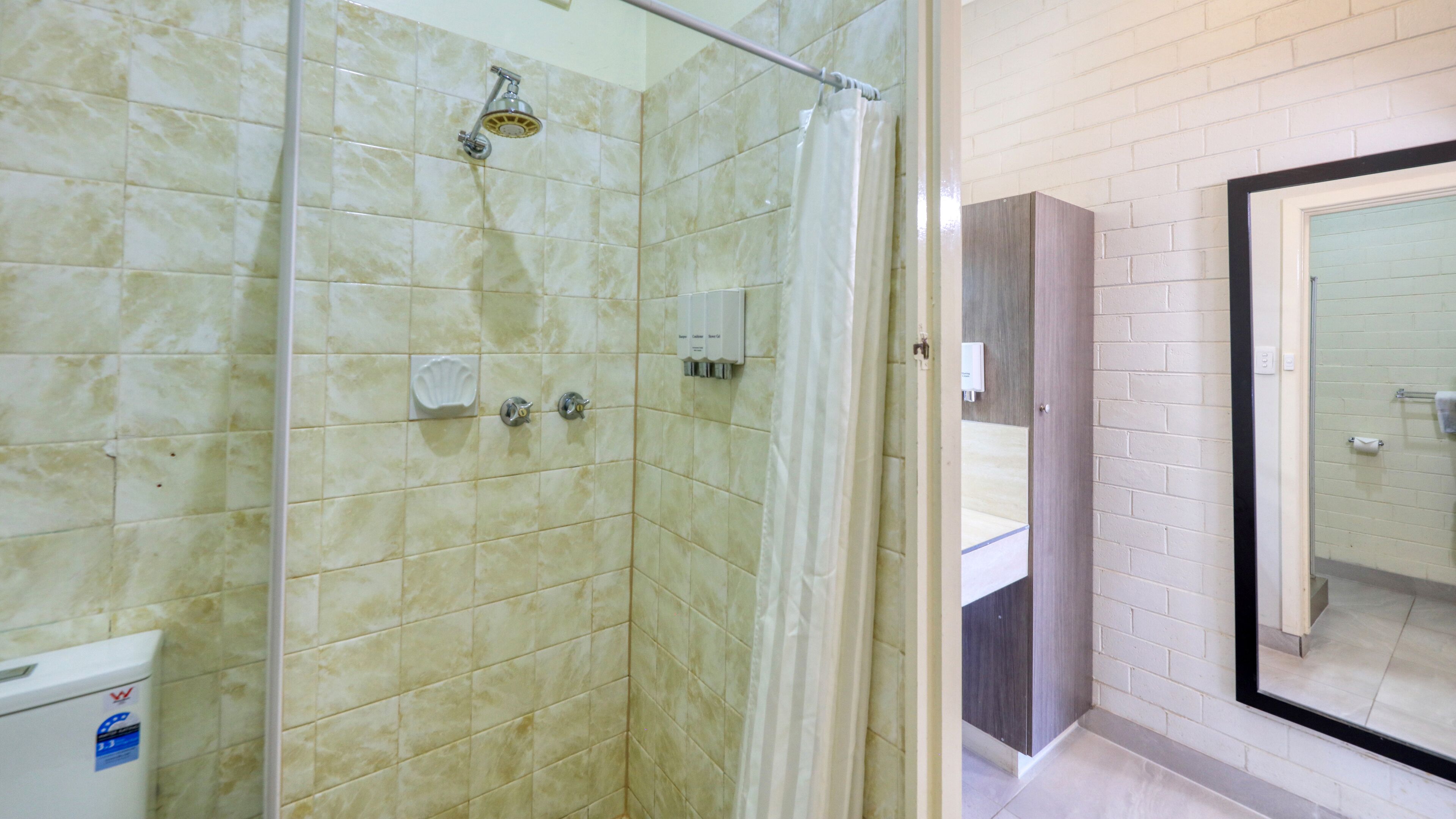 A bathroom with a glass shower enclosure, a toilet, and a sink.