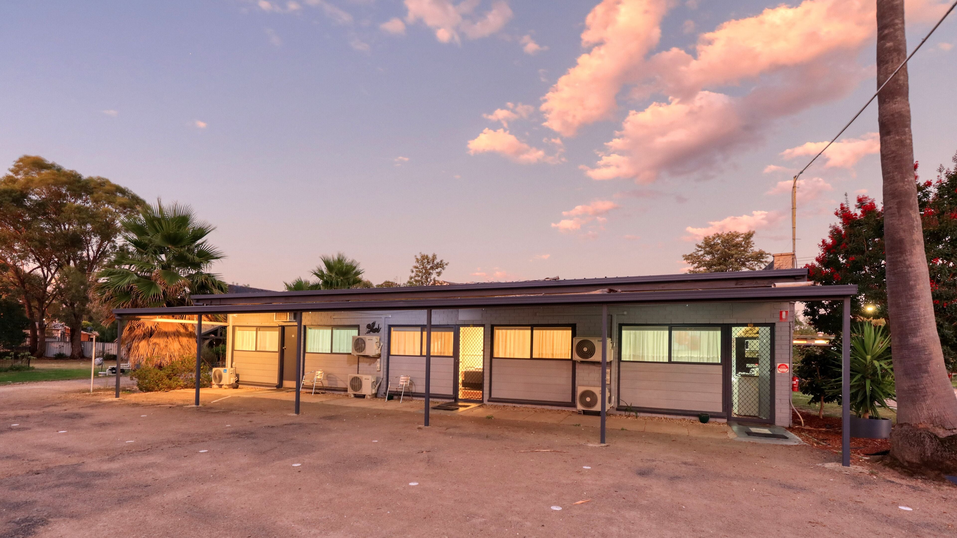 A single-story building with a flat roof, large windows, and air conditioning units.