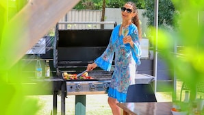 A person grilling vegetables on an outdoor grill. - Rose City Motor Inn (Benalla)