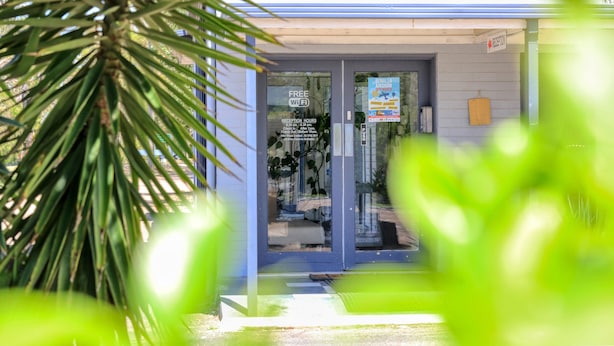 A reception area with a glass door, a sign indicating free WiFi, and reception hours. - Rose City Motor Inn (Benalla)