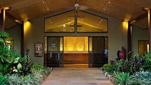 Una zona de recepción con techo de madera, puerta de cristal y mostrador de recepción.