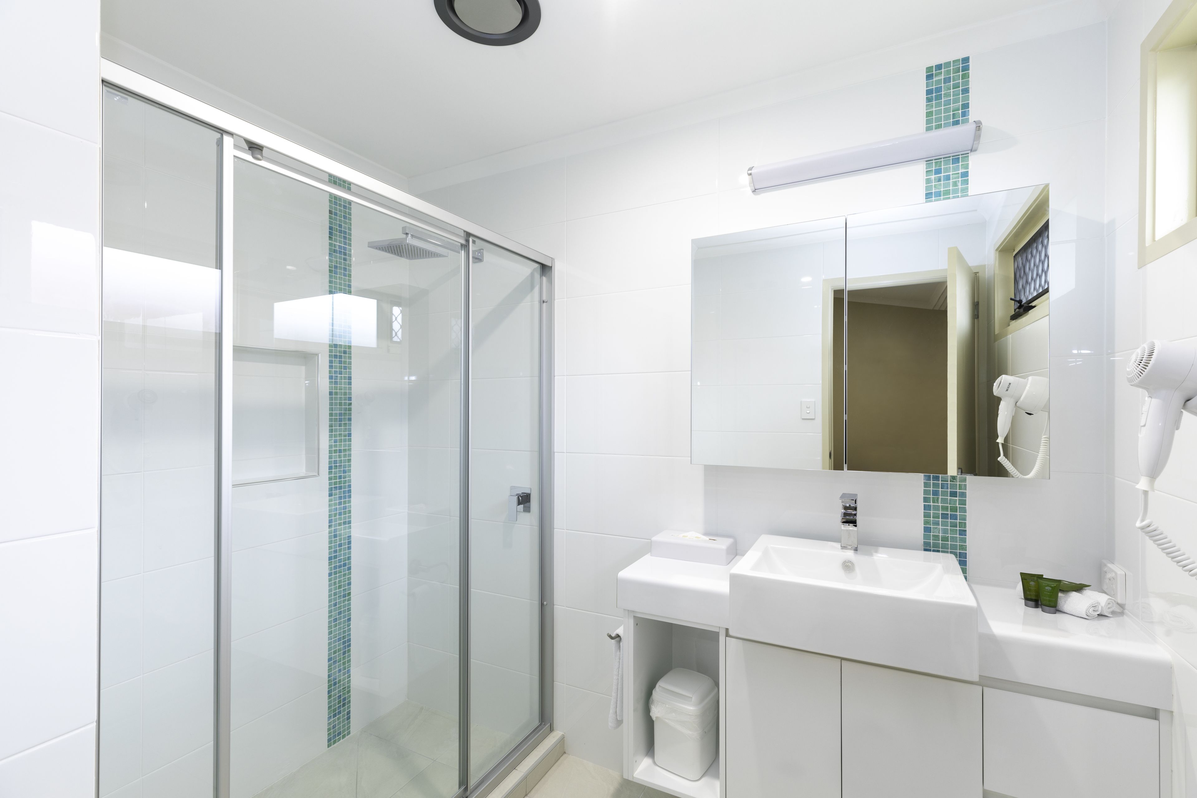 A modern bathroom with a glass shower enclosure, a white sink, and a mirror above the sink.